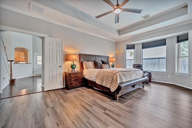 17815 Gables Bend Dr, Tomball, TX 77377 - bedroom featuring wood finished floors, a raised ceiling, arched walkways, baseboards, and crown molding