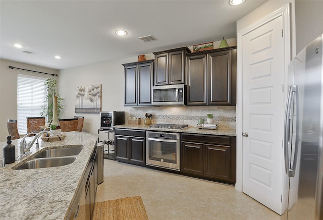 13705 Northline Lake Dr, Houston, TX 77044 - kitchen with stainless steel appliances, a sink, light stone countertops, dark brown cabinets, and recessed lighting