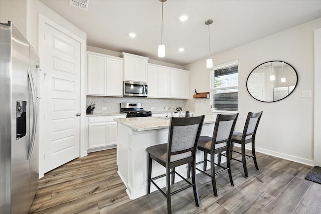9954 Storehouse Dr, Houston, TX 77080 - kitchen featuring stainless steel appliances, wood finished floors, tasteful backsplash, a center island with sink, and recessed lighting