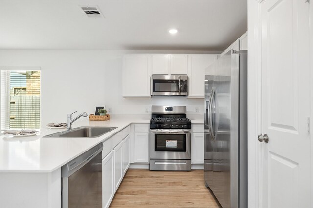1491 Twilight Green Dr, Katy, TX 77493 - kitchen with appliances with stainless steel finishes, a peninsula, a sink, light wood-type flooring, and light countertops