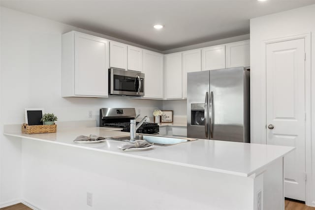 1491 Twilight Green Dr, Katy, TX 77493 - kitchen featuring stainless steel appliances, a peninsula, light countertops, a sink, and white cabinetry