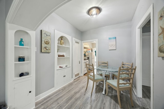 4404 Avenue N 1/2 Ave N 1/2, Galveston, TX 77550 - dining room featuring light wood-style floors, built in shelves, baseboards, and arched walkways