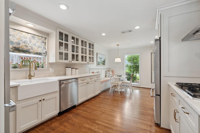 6147 Chevy Chase Dr, Houston, TX 77057 - kitchen with stainless steel appliances, a sink, glass insert cabinets, tasteful backsplash, and white cabinetry