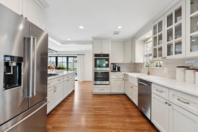 6147 Chevy Chase Dr, Houston, TX 77057 - kitchen with stainless steel appliances, wood finished floors, backsplash, white cabinetry, and recessed lighting