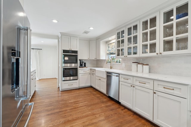 6147 Chevy Chase Dr, Houston, TX 77057 - kitchen with appliances with stainless steel finishes, backsplash, light wood finished floors, recessed lighting, and white cabinets