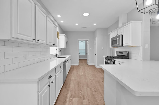 10 Hollylaurel Dr, The Woodlands, TX 77382 - kitchen with appliances with stainless steel finishes, a sink, white cabinetry, recessed lighting, and light wood-style flooring
