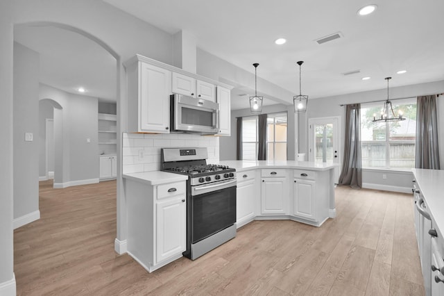 10 Hollylaurel Dr, The Woodlands, TX 77382 - kitchen with stainless steel appliances, arched walkways, light countertops, light wood-type flooring, and recessed lighting