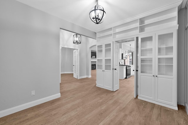 10 Hollylaurel Dr, The Woodlands, TX 77382 - unfurnished dining area with a chandelier, arched walkways, baseboards, and light wood-style flooring