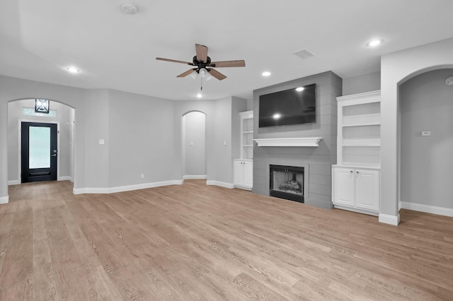 10 Hollylaurel Dr, The Woodlands, TX 77382 - unfurnished living room with ceiling fan, baseboards, arched walkways, light wood-type flooring, and recessed lighting