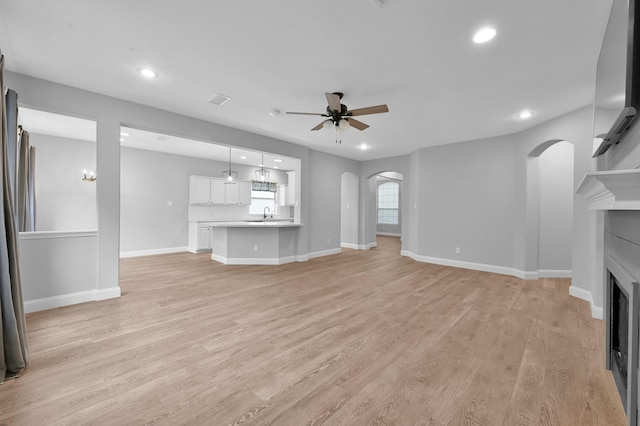 10 Hollylaurel Dr, The Woodlands, TX 77382 - unfurnished living room with ceiling fan, arched walkways, a fireplace, recessed lighting, and light wood-style floors