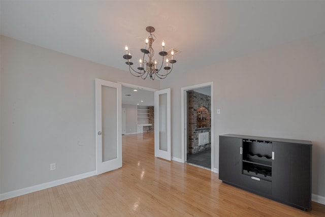 10126 Whiteside Ln, Houston, TX 77043 - unfurnished dining area with a chandelier, light wood finished floors, french doors, and baseboards