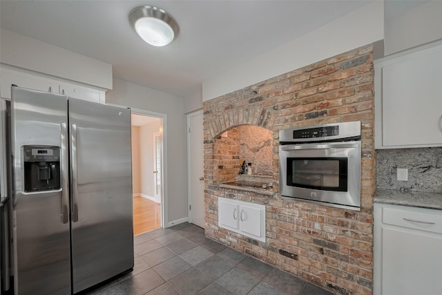10126 Whiteside Ln, Houston, TX 77043 - kitchen with stainless steel appliances, dark tile patterned floors, white cabinets, and light stone countertops
