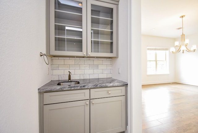 7818 Ludington Dr, Houston, TX 77071 - bar with a sink, backsplash, a chandelier, light wood-style flooring, and decorative light fixtures