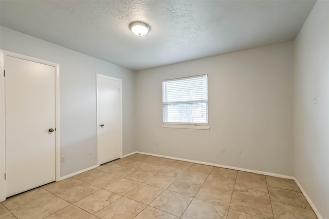 10901 Mesquite Dr, La Porte, TX 77571 - unfurnished bedroom featuring baseboards, light tile patterned floors, and a textured ceiling