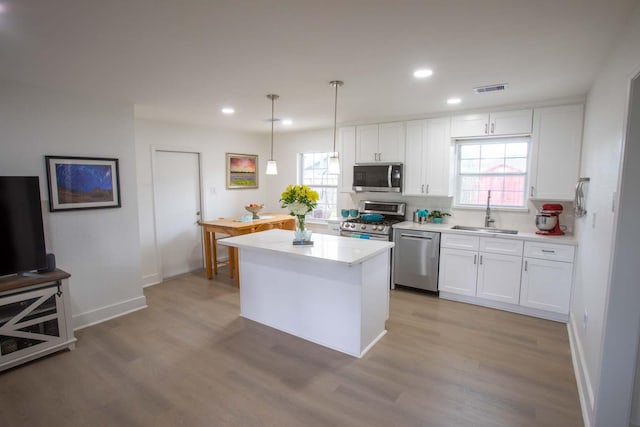 2302 Hewitt Dr, Houston, TX 77018 - kitchen with stainless steel appliances, a sink, white cabinetry, light wood-style flooring, and light countertops