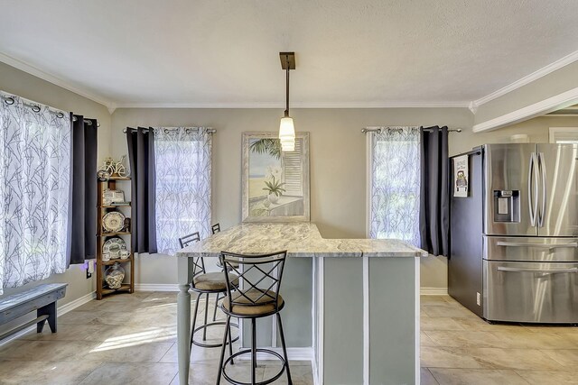 1239 Indian Hill Blvd, Livingston, TX 77351 - kitchen featuring stainless steel refrigerator with ice dispenser, healthy amount of natural light, ornamental molding, light stone countertops, and a kitchen bar