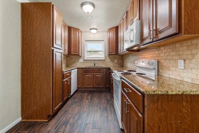1121 E 13th St, Deer Park, TX 77536 - kitchen featuring white appliances, dark wood-style flooring, decorative backsplash, brown cabinetry, and a textured ceiling