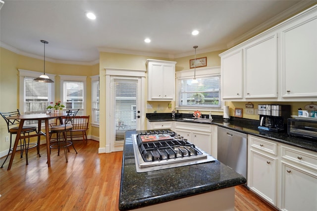 606 E 27th St, Houston, TX 77008 - kitchen featuring stainless steel appliances, white cabinets, light wood-style floors, crown molding, and a center island