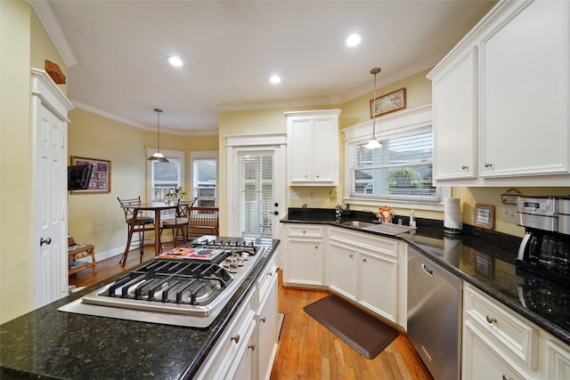 606 E 27th St, Houston, TX 77008 - kitchen featuring stainless steel appliances, light wood finished floors, crown molding, plenty of natural light, and white cabinets