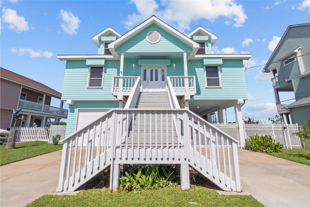 1022 Darcy St, Galveston, TX 77554 - coastal inspired home with stairs, concrete driveway, covered porch, and an attached garage