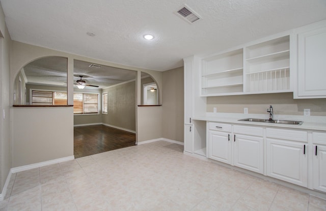 2020 Vince St, Pasadena, TX 77502 - kitchen with a sink, arched walkways, a textured ceiling, baseboards, and white cabinetry