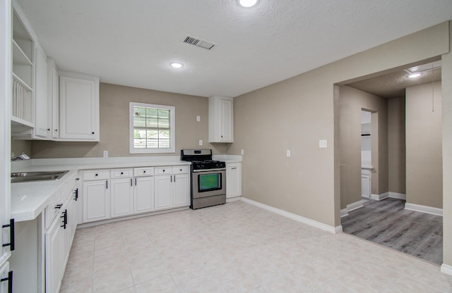 2020 Vince St, Pasadena, TX 77502 - kitchen featuring stainless steel range with gas stovetop, a sink, open shelves, light countertops, and white cabinetry