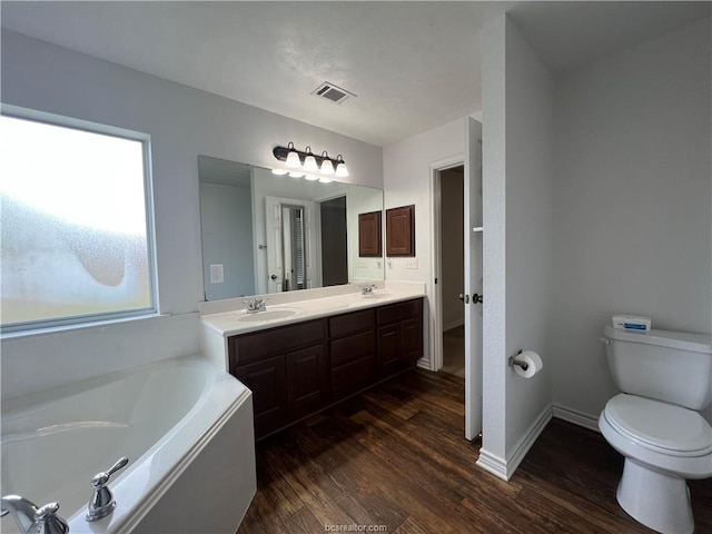1027 Emerald Dove Ave, College Station, TX 77845 - bathroom featuring a garden tub, double vanity, wood finished floors, and toilet