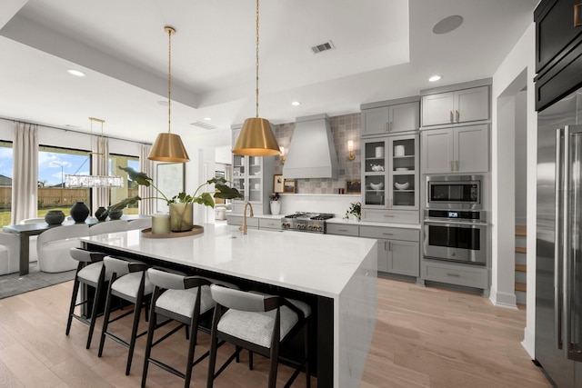 1902 Kessler Point Pl, Katy, TX 77493 - kitchen featuring built in appliances, a raised ceiling, gray cabinetry, premium range hood, and recessed lighting