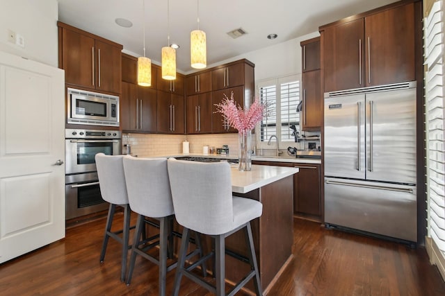 4129 Dickson St, Houston, TX 77007 - kitchen featuring built in appliances, light countertops, dark wood-style floors, and decorative backsplash
