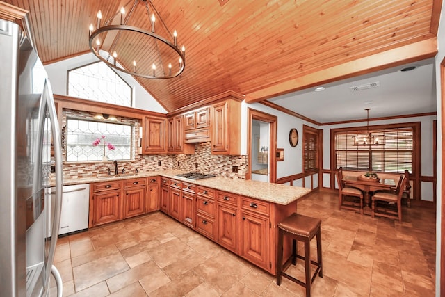 1207 W Edgewood Dr, Friendswood, TX 77546 - kitchen with a chandelier, appliances with stainless steel finishes, a peninsula, light stone counters, and plenty of natural light