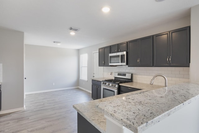 5903 Bonners Park Ct, Katy, TX 77449 - kitchen featuring stainless steel appliances, tasteful backsplash, light stone counters, light wood finished floors, and baseboards