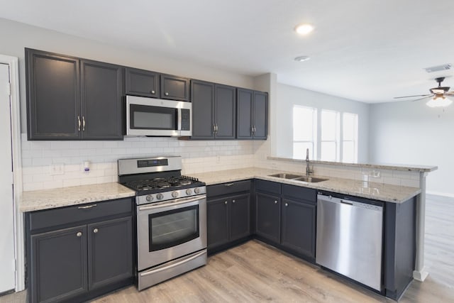 5903 Bonners Park Ct, Katy, TX 77449 - kitchen featuring appliances with stainless steel finishes, a sink, a peninsula, light wood-type flooring, and tasteful backsplash