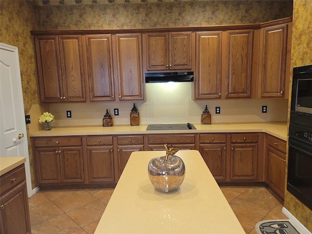 3501 Carson Ct, Pearland, TX 77584 - kitchen with under cabinet range hood, wallpapered walls, black appliances, light countertops, and light tile patterned floors