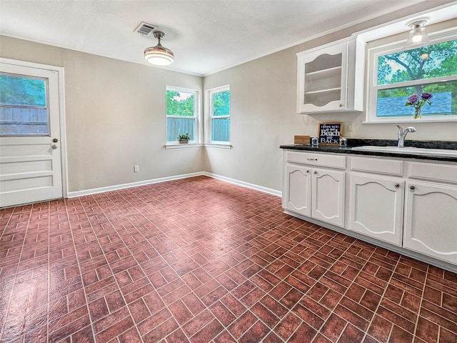 723 Pas Trl, Houston, TX 77336 - kitchen with a sink, brick patterned flooring, dark countertops, white cabinets, and baseboards