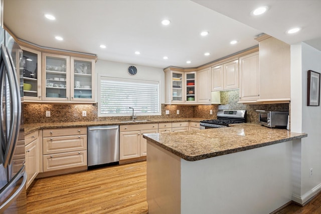 2415 Avalon Pl, Houston, TX 77019 - kitchen featuring appliances with stainless steel finishes, light wood-type flooring, a peninsula, a sink, and tasteful backsplash