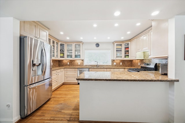 2415 Avalon Pl, Houston, TX 77019 - kitchen with stainless steel appliances, a peninsula, light wood-style floors, a sink, and tasteful backsplash