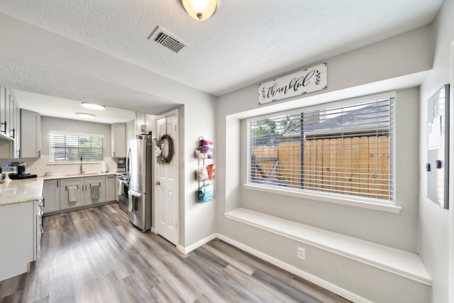 3808 Cottonwood Dr, La Porte, TX 77571 - kitchen featuring freestanding refrigerator, gray cabinets, wood finished floors, a sink, and a textured ceiling