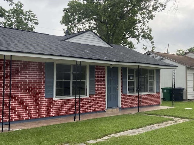 5715 Belmark St, Houston, TX 77033 - ranch-style home featuring brick siding, a front yard, roof with shingles, and covered porch