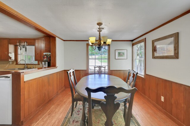 151 Lakeview Cir, Coldspring, TX 77331 - dining space with a wainscoted wall, wooden walls, light wood-type flooring, a chandelier, and crown molding