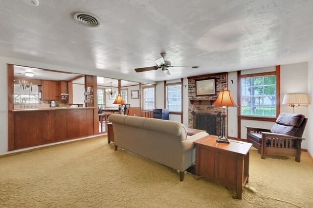 151 Lakeview Cir, Coldspring, TX 77331 - living area featuring light colored carpet, a brick fireplace, a ceiling fan, and a chandelier