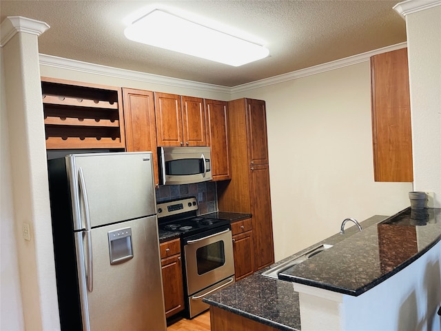 1711 Old Spanish Trl Unit 127, Houston, TX 77054 - kitchen featuring appliances with stainless steel finishes, a peninsula, brown cabinets, dark stone counters, and ornamental molding