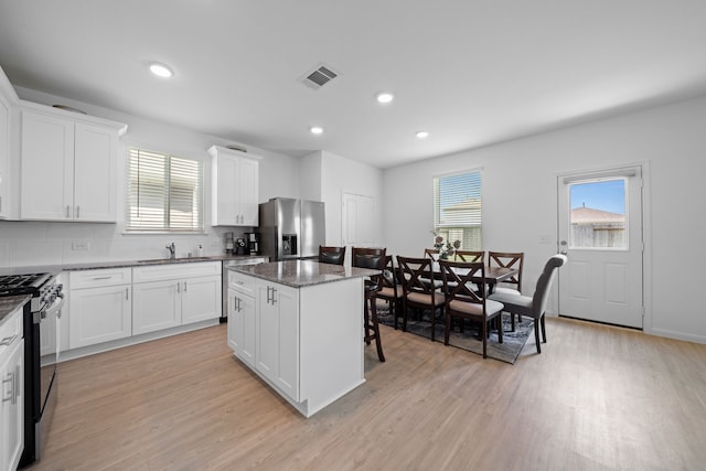 23515 Weir Box Rd, Hockley, TX 77447 - kitchen featuring appliances with stainless steel finishes, a sink, a center island, light wood-style flooring, and white cabinetry