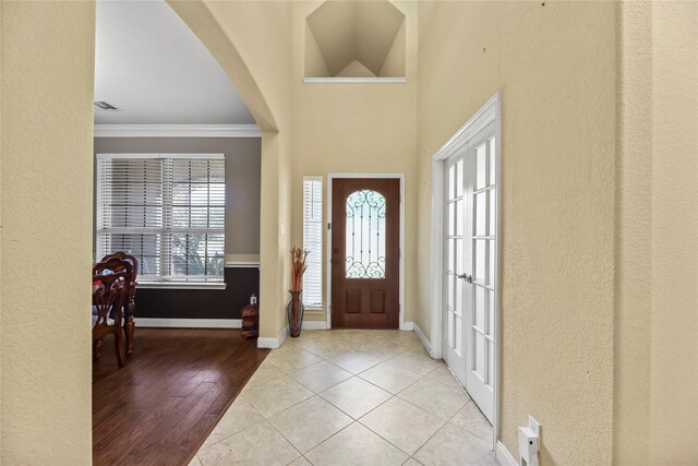 26020 Bassfield Ln, Katy, TX 77494 - foyer entrance featuring ornamental molding, baseboards, tile patterned floors, arched walkways, and a textured wall