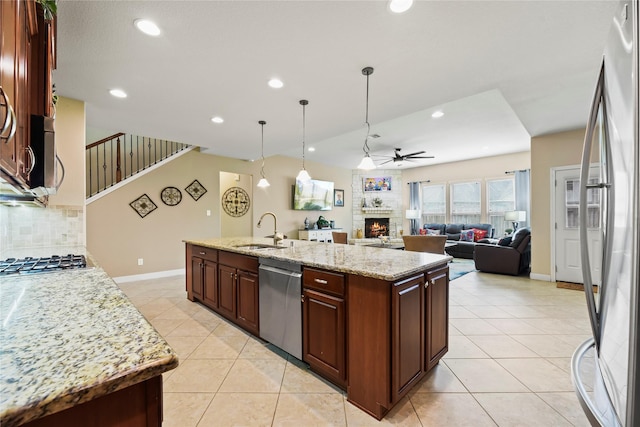 26020 Bassfield Ln, Katy, TX 77494 - kitchen featuring appliances with stainless steel finishes, a sink, ceiling fan, a fireplace, and backsplash