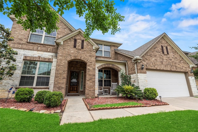 26020 Bassfield Ln, Katy, TX 77494 - view of front of house featuring concrete driveway, covered porch, brick siding, an attached garage, and stone siding