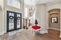 57 Cloverdale Ct, Montgomery, TX 77356 - foyer entrance featuring french doors, arched walkways, baseboards, wood finished floors, and plenty of natural light