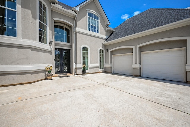 57 Cloverdale Ct, Montgomery, TX 77356 - property entrance featuring french doors, concrete driveway, stucco siding, a garage, and a shingled roof