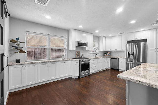 1139 Lehman St, Houston, TX 77018 - kitchen featuring appliances with stainless steel finishes, a sink, dark wood-style flooring, white cabinetry, and recessed lighting