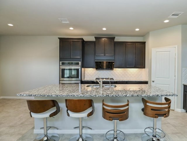 5422 Wildbrush Dr, Richmond, TX 77407 - kitchen with stainless steel oven, a sink, light stone countertops, backsplash, and recessed lighting