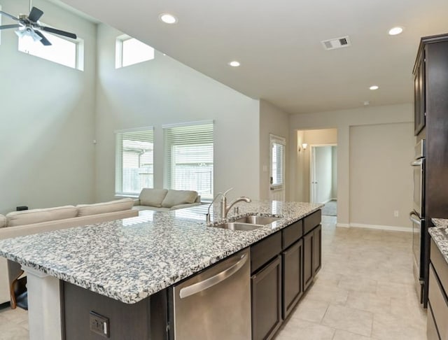 5422 Wildbrush Dr, Richmond, TX 77407 - kitchen featuring stainless steel appliances, a sink, a center island with sink, open floor plan, and dark brown cabinets